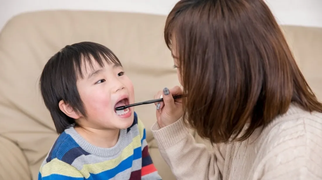 母親に歯を磨いてもらう幼児