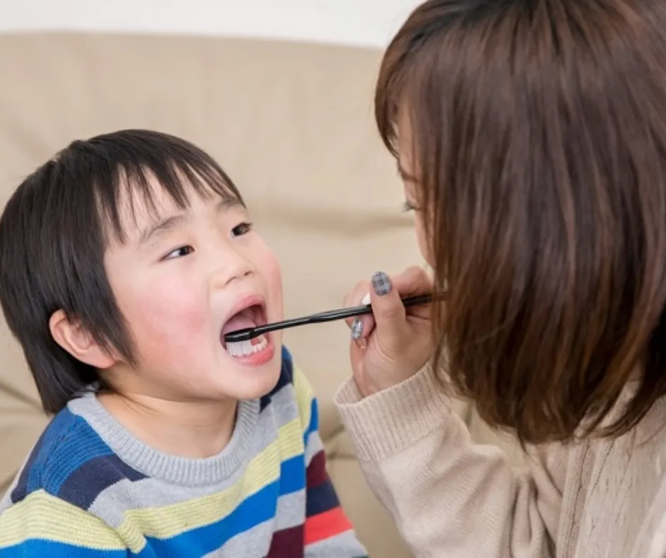 母親に歯を磨いてもらう幼児