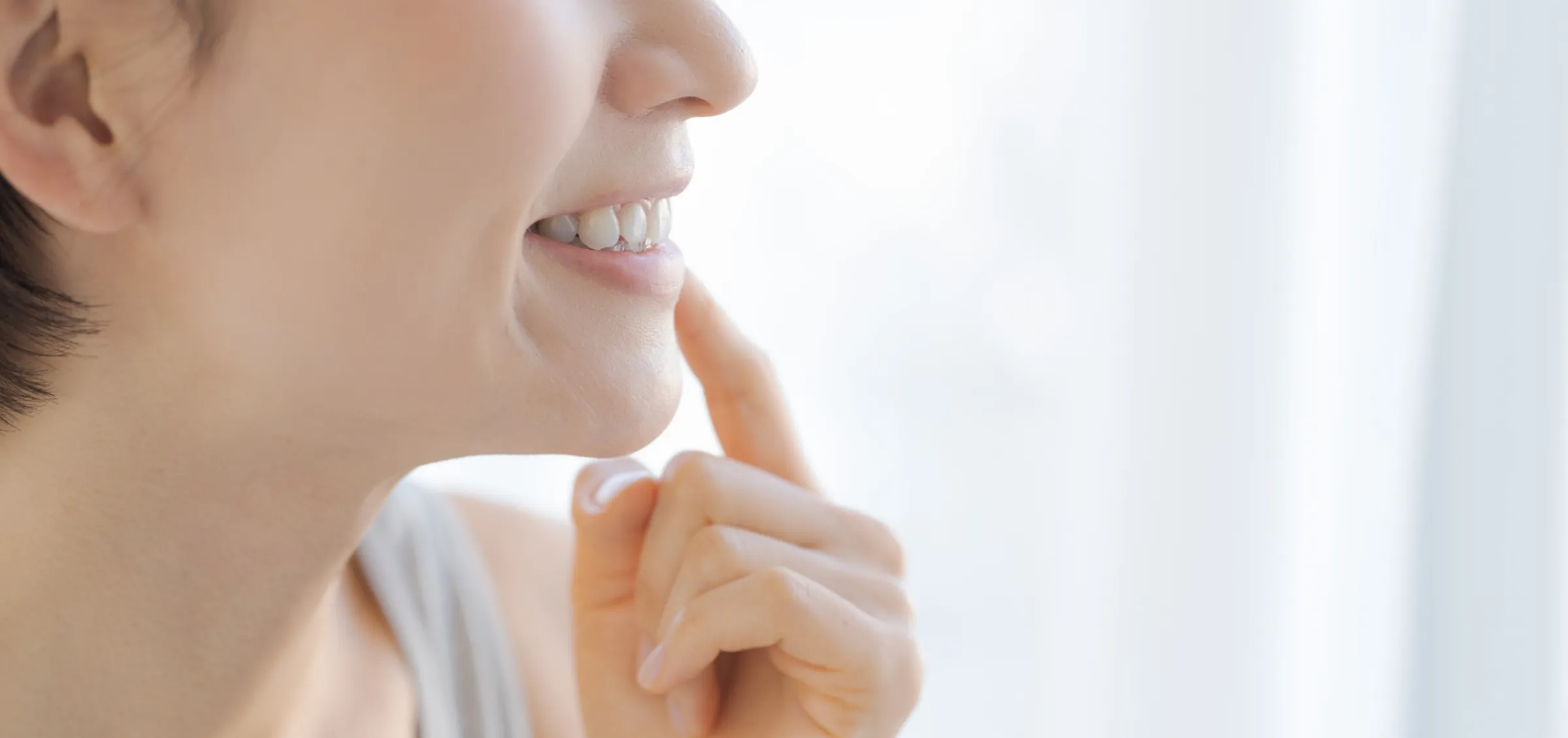 白い歯で笑う女性の口元